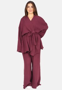 Burgunderfarbene Zweiteiler aus strukturiertem Stoff; besteht aus einem lockeren, wickelähnlichen Oberteil mit Bindeband und weit geschnittenen Hosen.