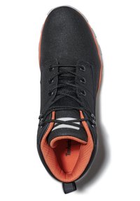 Baskets noires en synthétique avec une tige texturée, intérieur orange, lacets noirs et accents réfléchissants. Semelle en caoutchouc avec une languette au talon.