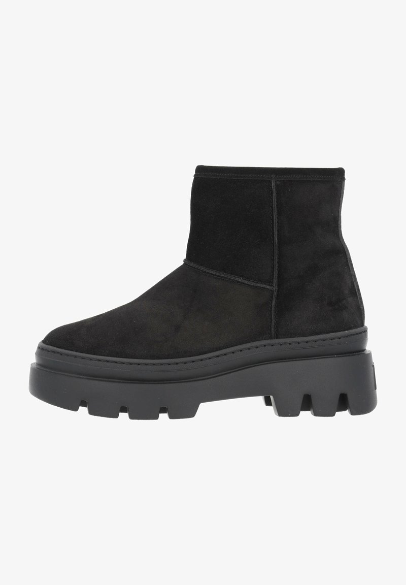 Bota corta de ante negro con una gruesa suela negra de plataforma, diseño minimalista, textura suave y sin herrajes ni patrones visibles.
