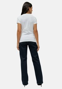 Camiseta blanca ajustada combinada con pantalones vaqueros de pierna ancha azul oscuro, con una textura suave y un diseño clásico de cinco bolsillos.