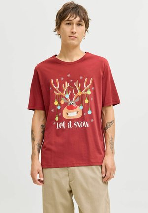 T-shirt rouge à manches courtes avec un graphique de renne de dessin animé, des boules de Noël suspendues et le texte "Laissez tomber la neige" en blanc.