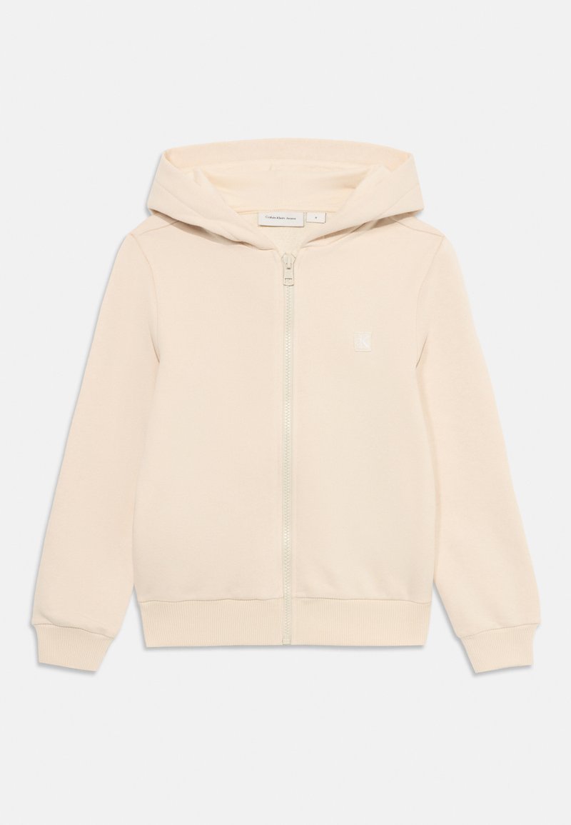 Svetlo béžová mikina na zips s klokankovým vreckom, ribbovanými manžetami a lemom. Obsahuje diskrétny logo na hrudi a kapucňu so sťahovacou šnúrkou.