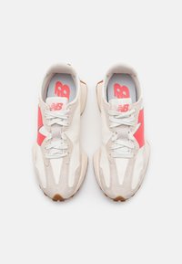 Vita och ljusgrå sportskor med rosa accenter, i mocka och mesh-material, rundad design och texturerade gummisulor.