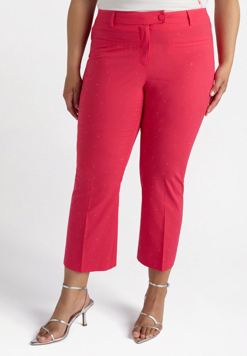 Röda capribyxor i ett mjukt tyg, prydda med små silvernitar, har två framfickor och en figurnära midja.