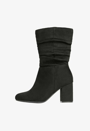 Juodas dirbtinės suedes kulkšninis botas su sulenkta dizainu, smailiu nosiu ir kvadratiniu kulnu. Pasižymi lygiu tekstūru ir minimaliomis siuvimo detalėmis.