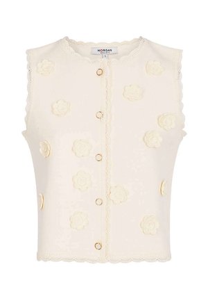 Cardigan sans manches crème avec bords festonnés, fermetures à boutons anneaux dorés et appliqués floraux 3D sur le devant et les côtés.