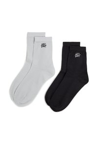 Chaussettes en coton noires et grises avec des bord-côtes, présentant un petit logo noir sur chaque chaussette. Texture lisse, longueur standard de type mi-mollet.