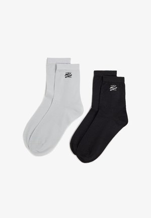Calzini in cotone neri e grigi con polsini a coste, caratterizzati da un piccolo logo nero su ciascun calzino. Texture liscia, lunghezza standard alla caviglia.