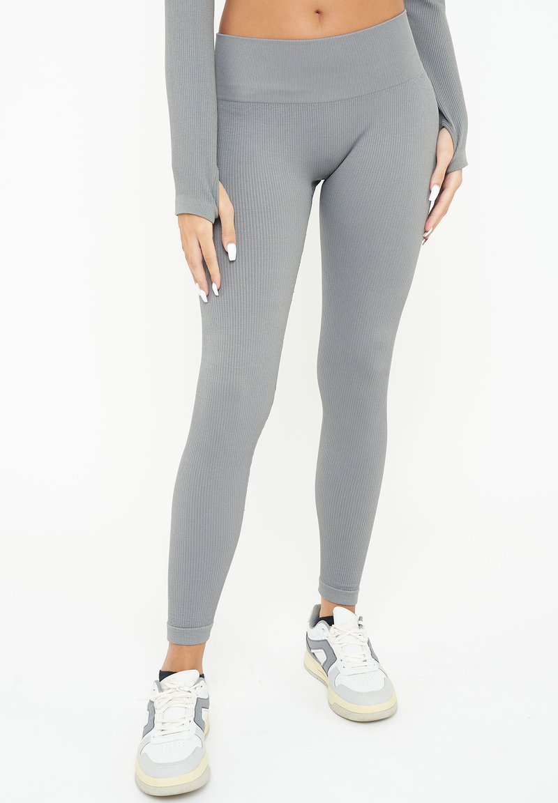 Grå randiga leggings med hög midja, som har en figurnära design och slät textur, tillsammans med vita och grå träningsskor.