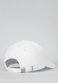 Cappellino da baseball bianco in cotone, con visiera curva, cinturino regolabile e un'etichetta metallica con testo sul retro.