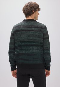 Mörkgrön stickad tröja med svarta och ljusare gröna horisontella ränder, rund hals, samt ribbade muddar och nederkant. Strukturerad tyg.
