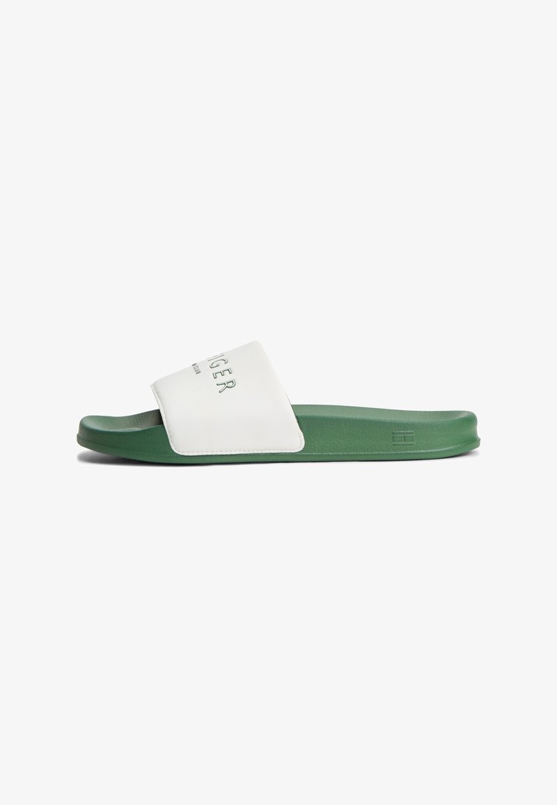 Sandale slide verte avec une large bride blanche comportant le nom de la marque et le logo en relief sur le côté de la semelle.