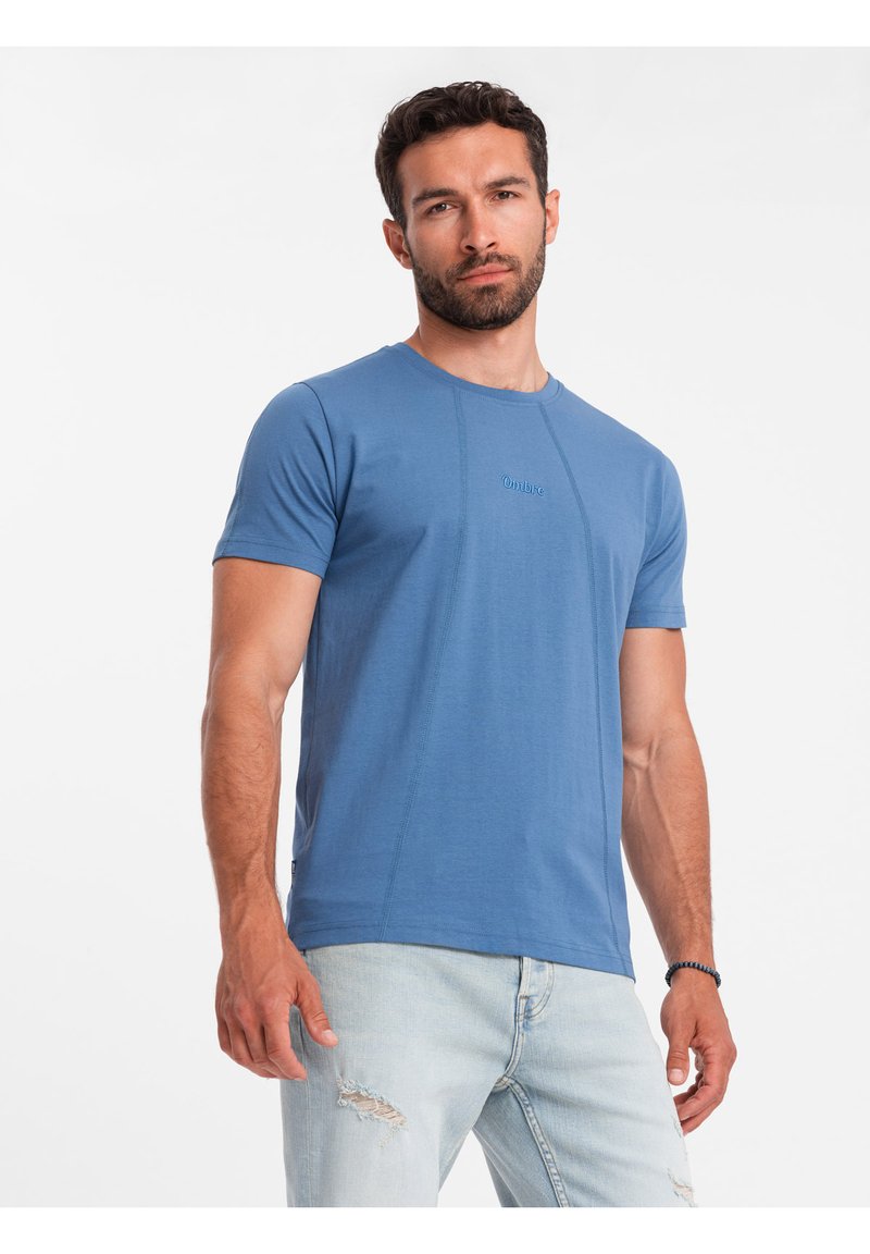 Modrá bavlněná tričko s krátkými rukávy, s kulatým výstřihem a jemnými detaily šití. Logo na hrudi, v kombinaci se světlými džíny.