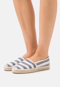 Espadrillas con una toma superiore in tessuto bianco a righe diagonali blu, suola in corda di juta e un design a punta tonda.