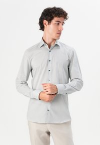 Long-sleeve button-up shirt in light gray with small dark blue geometric pattern and contrasting blue buttons. Tailored fit with a collar.