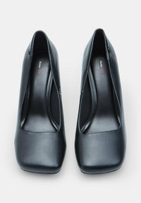 Scarpe nere con tacco alto, dalla punta squadrata, realizzate in pelle liscia. Presentano eleganti intagli sui lati e una finitura lucida.
