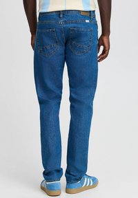 Jeans de mezclilla azul oscuro con un diseño de pierna recta, dos bolsillos traseros con costuras verticales y un acabado sutilmente texturizado.