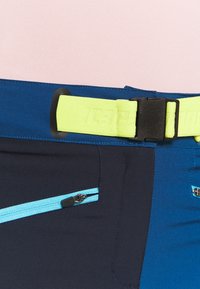 Pantalones cortos técnicos en azul marino y azul, con un cinturón amarillo y una hebilla negra, bolsillos con cremallera con acentos azules y una textura suave.