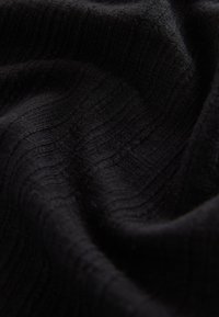 Tissu noir avec un motif texturé côtelé. Le matériau semble doux et légèrement brillant, avec des variations subtiles dans la profondeur de la surface.