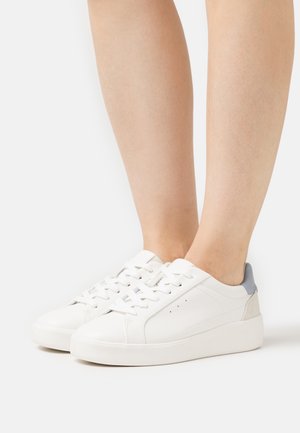 Sneakers bianche in pelle con una texture liscia, caratterizzate da accenti grigi sul tallone e sugli occhielli, punta rotonda e suola piatta in gomma.