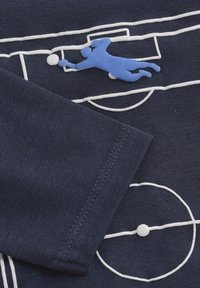 Tengerészkék ing fehér hímzett focipálya mintával és kék textil applikációval, ami egy kapus védését ábrázolja.