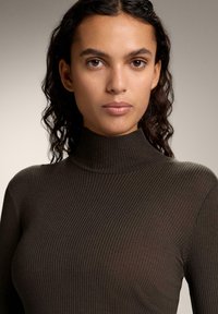 Brauner gerippter Rollkragenpullover, figurbetontes Design, weiche Textur, hoher Kragen, mit glatter Oberfläche und subtilen vertikalen Mustern.