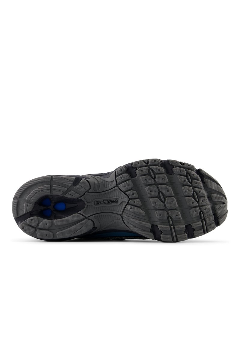 Sole di scarpa sportiva grigia e nera con gomma testurizzata, caratterizzata da un motivo di impugnature esagonali e ovali, e dettagli di ammortizzazione blu.