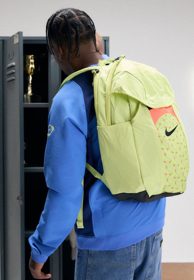 Rucsac Nike într-o nuanță vie de verde lime, cu un material texturat, având accente neon și un model geometric pe partea din față.