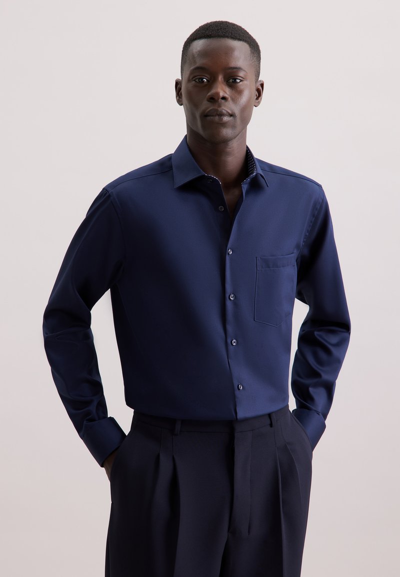 Maglietta a maniche lunghe blu navy in un tessuto liscio con chiusura a bottoni, taschino sul petto e dettaglio interno del collo a contrasto con motivo.