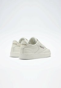 Białe skórzane trampki z teksturowaną podeszwą, o prostym wzornictwie, okrągłym nosku i brązowym logo Reebok z boku i na języku.