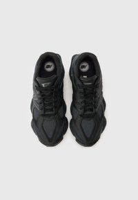 Mustade ja tumehallide New Balance spordijalatsite paar, millel on võrgust ja nahast detailid, vaadatuna ülevalt valgel taustal.