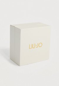 Krémově zbarvená texturovaná krabička se zlatým logem značky LIU·JO umístěným zcentrálně na přední straně, umístěná na jednobarevném bílém pozadí.