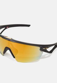 Schwarze Sportsonnenbrille mit übergroßem orangenem Verlaufsglas, leichtem Design und konturiertem Rahmen für einen sicheren Sitz.