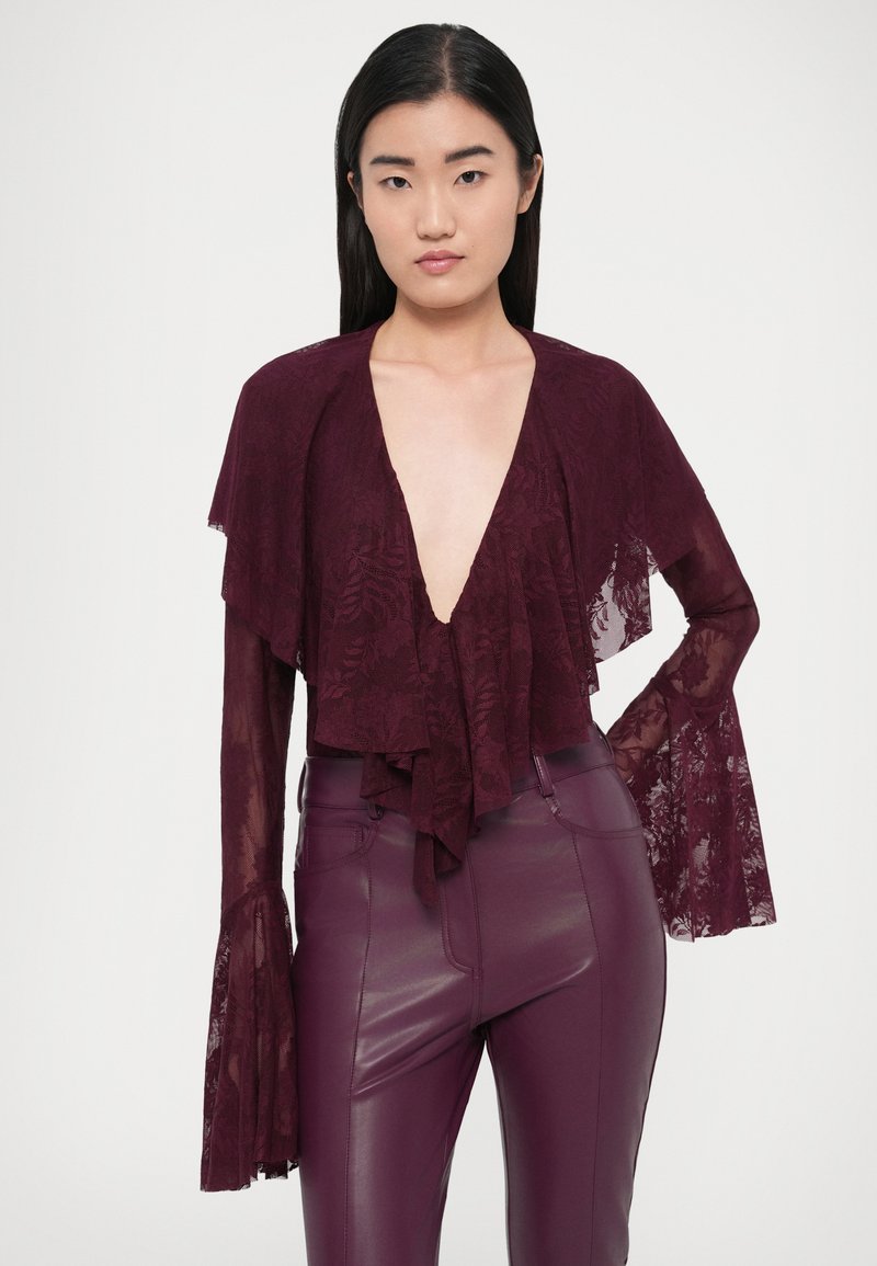 Bordeauxrode kanten top met gerafelde randen en wijde mouwen, met een diepe V-hals en bloemenpatroon, gecombineerd met bijpassende broek met hoge taille.