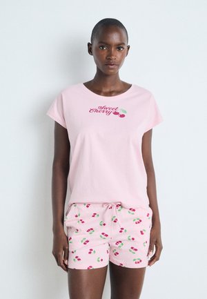 Pink cotton t-shirt with "Sweet Cherry" print and matching shorts featuring cherry motifs and a drawstring waist, smooth texture.