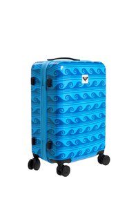 Valise rigide bleue avec des motifs ondulés bleu foncé, poignée noire et quatre roulettes noires pivotantes.