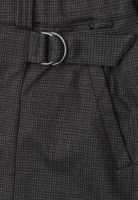 Gros plan sur un tissu à carreaux gris foncé avec une ceinture plissée et une boucle de ceinture en métal argenté en forme d'anneau en D.