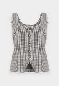 Αμάνικη μαύρη και λευκή καρώ μπλούζα με πέντε κουμπιά στο κέντρο και μικρό τρίγωνο άνοιγμα στο κάτω μέρος μπροστά.