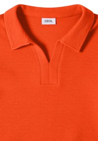Lyseorange tekstureret polo med en blød krave og V-udskæring, med et hvidt mærke med "CECIL" ved halsudskæringen.