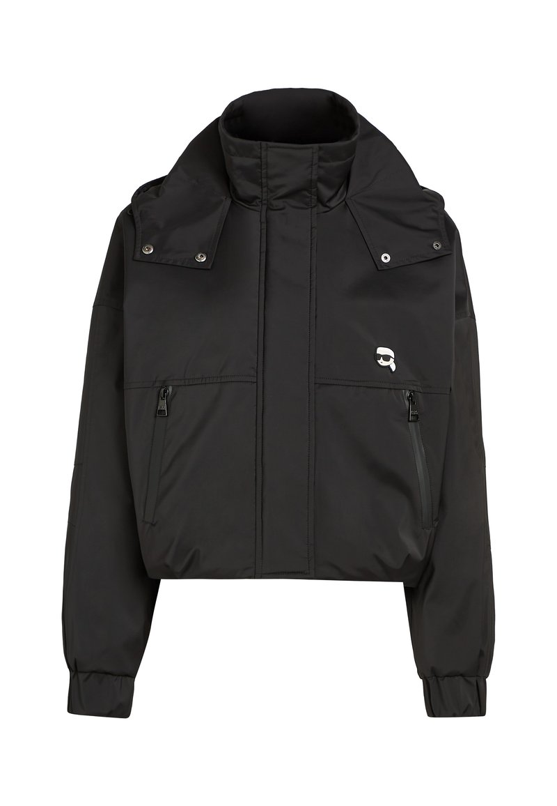 Mustmust jakk, mis on valmistatud sileda ja kerge kangaga. Omab kõrget krae, kahte esist zip-taskut ja logo vasakul küljel.