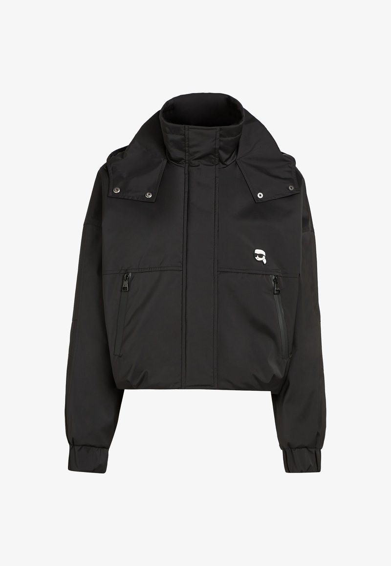 Mustmust jakk, mis on valmistatud sileda ja kerge kangaga. Omab kõrget krae, kahte esist zip-taskut ja logo vasakul küljel.