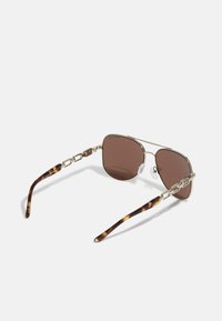 Occhiali da sole aviator con tonalità marroni e montatura in metallo dorato, catena decorativa sui lati e punte delle asticelle con motivo tartaruga.