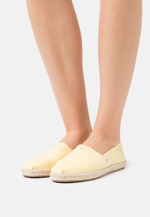 Geel canvas instap schoenen met een jute touwzool, beschikken over een gladde textuur en driehoekige gestikte accenten op de bovenkant.