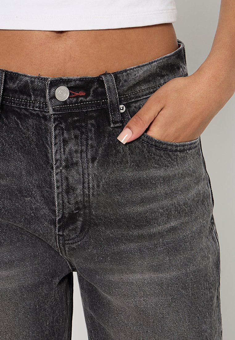 Jeans in denim nero con una trama sbiadita, design a cinque tasche e chiusura con bottone argento. Posizionati a mano nell'area della tasca anteriore.