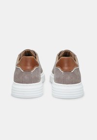 Zapatillas de cuero marrón con diseño perforado, suela de goma blanca, puntera redondeada y acentos en color marrón claro en el talón y la parte superior.