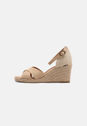Beige kile-sandal med krydsede forremmestraps, vævet tekstureret hæl og ankelrem med lille rund spænde.