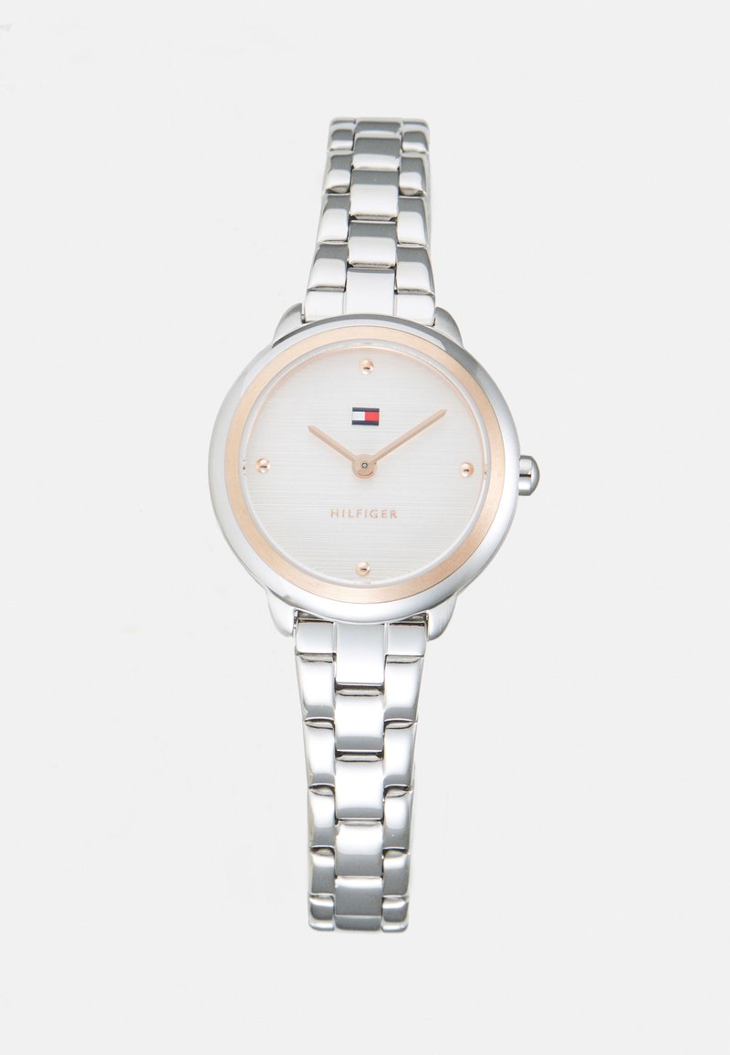 Silver metal linked wristwatch with round white face, gold-tone hour markers and hands, and a small red, white, and blue logo at 12 o'clock.