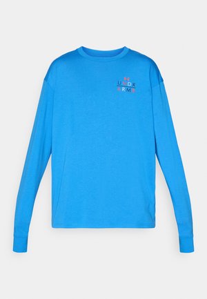 Blå långärmad skjorta i mjukt tyg. Har en ribbad rundhals och en liten logotyp i rött och svart på bröstet.