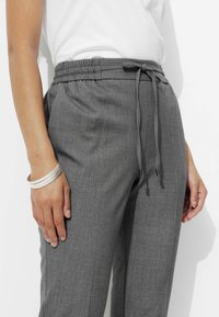 Pantalons gris à cordon de serrage avec une texture douce et une taille élastique, dotés d'une coupe slim et ornés de cordons de serrage avec embouts en métal.