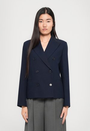 Blazer doppiopetto blu navy con colletto a punte, due grandi tasche frontali e dettagli con bottoni. Tessuto liscio con vestibilità strutturata.